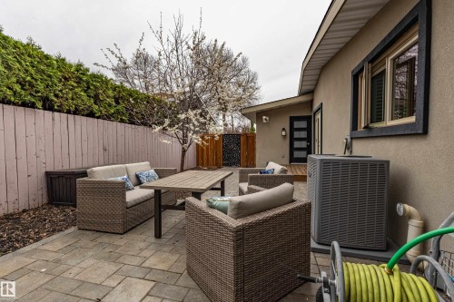 Paver patio offering an exterior living area with a wood fence, mature evergreen shrubbery, and a blossoming tree - 10 Brunswick Crescent, St. Albert, AB - Outdoor With Deck Patio Veranda With Exterior