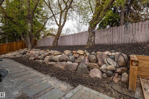 Landscaped yard featuring a stone retaining wall and mature trees - 10 Brunswick Crescent, St. Albert, AB - Outdoor