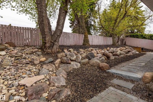 Landscaped backyard featuring a stone rockery, mature trees, and a wooden privacy fence - 10 Brunswick Crescent, St. Albert, AB - Outdoor
