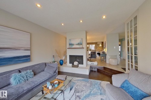 Living space featuring a central fireplace with a hearth, dark wood-finish flooring, recessed ceiling lighting, and French doors - 10 Brunswick Crescent, St. Albert, AB - Indoor Photo Showing Living Room With Fireplace