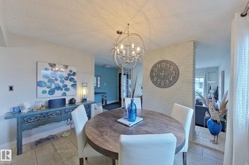 Dining area featuring a circular wood-finish table, a contemporary spherical chandelier, and light-toned tile flooring - 10 Brunswick Crescent, St. Albert, AB - Indoor Photo Showing Dining Room