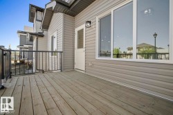 Spacious outdoor deck featuring natural wood planks and black metal railings - 