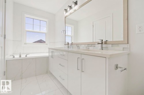 Bright bathroom featuring a double vanity with stone countertops, undermount sinks, and chrome fixtures - 151 Kidd Crescent, Leduc, AB - Indoor Photo Showing Bathroom