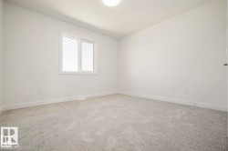 Spacious room with light gray carpeting, a single window with white trim, white walls, and a flush-mount ceiling light fixture - 