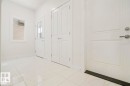 Crisp white interior space featuring large format floor tiling, a paneled entry door with modern hardware, and a small window - 151 Kidd Crescent, Leduc, AB  - Indoor Photo Showing Other Room 