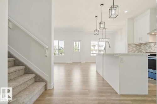 Open concept living space featuring wood-finish flooring, a kitchen island with stone countertops, and pendant lighting - 151 Kidd Crescent, Leduc, AB - Indoor Photo Showing Kitchen