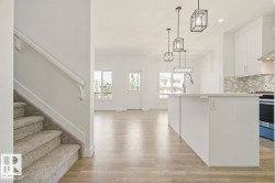 Open concept living space featuring wood-finish flooring, a kitchen island with stone countertops, and pendant lighting - 