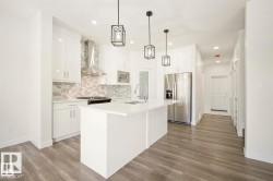 Modern kitchen featuring a white island with a sink and faucet, white cabinetry, stainless steel appliances, a mosaic tile backsplash, and wood-finish flooring - 