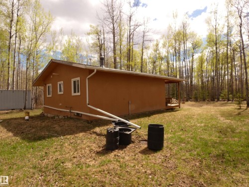 View of the rear of the cottage showing the water capture barrels----Moose and deer are known to "drop by" for a drink! - 307 Willow Place, Rural Barrhead County, AB 
