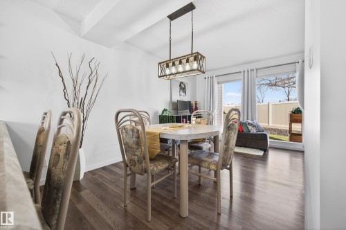 Dining area featuring wood-finish flooring, a rectangular light fixture with exposed bulbs, and a vaulted ceiling - 14522 56 Street, Edmonton, AB - Indoor Photo Showing Dining Room