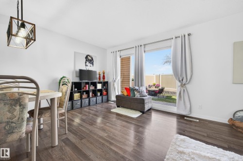 Open-concept living space featuring wood-finish flooring, a contemporary ceiling light fixture, and a large sliding glass door offering direct access to the outdoor area - 14522 56 Street, Edmonton, AB - Indoor