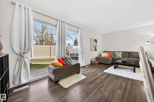 Expansive living area with wood-finish flooring and large sliding glass doors providing access to the exterior - 14522 56 Street, Edmonton, AB - Indoor Photo Showing Living Room