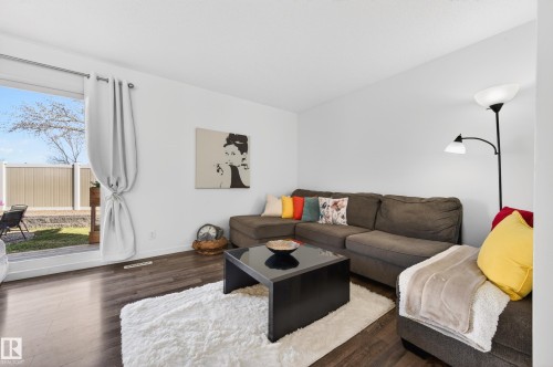 Bright living area featuring wood-finish flooring, white walls, and a sliding glass door leading to an outdoor space - 14522 56 Street, Edmonton, AB - Indoor Photo Showing Living Room
