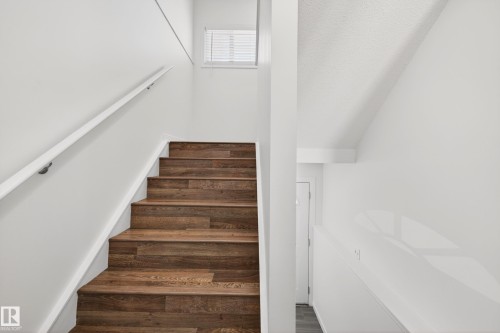 Staircase featuring wood-finish treads and risers, white handrail, and a window with horizontal blinds - 14522 56 Street, Edmonton, AB - Indoor Photo Showing Other Room