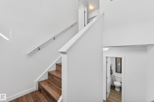 Multi-level interior featuring wood-finish staircase treads, white risers, and a white handrail - 14522 56 Street, Edmonton, AB - Indoor Photo Showing Other Room