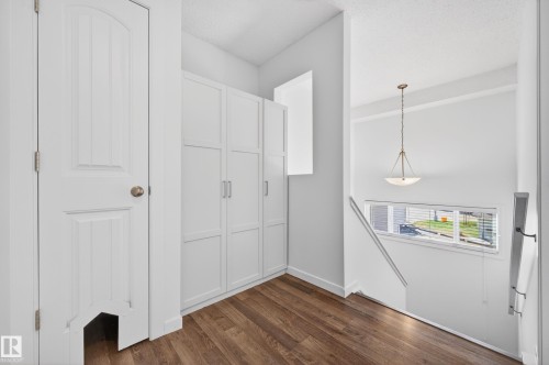Hallway featuring wood-finish flooring, white built-in cabinetry, and a horizontal window providing natural illumination - 14522 56 Street, Edmonton, AB - Indoor Photo Showing Other Room