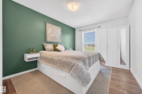 Bedroom featuring a contrasting accent wall, wood-finish flooring, and a window with horizontal blinds - 14522 56 Street, Edmonton, AB - Indoor Photo Showing Bedroom