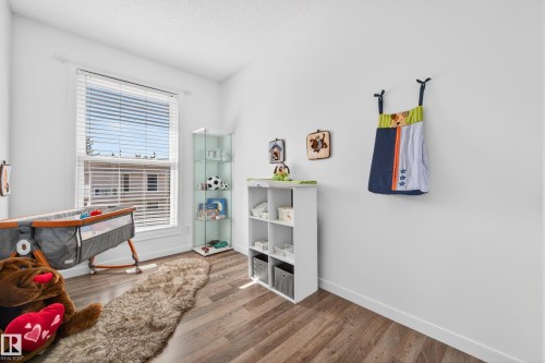 Bright room featuring a large window with blinds, wood-finish flooring, and white baseboards - 14522 56 Street, Edmonton, AB - Indoor