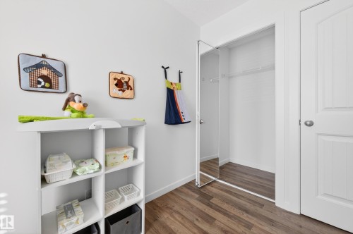 Interior room featuring wood-finish flooring, white walls, mirrored closet door with small walk-in-closet and white paneled entry door - 14522 56 Street, Edmonton, AB - Indoor