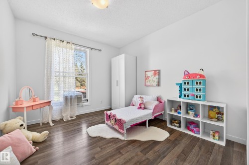 Spacious room featuring wood-finish flooring, white walls, and a large window with sheer curtains - 14522 56 Street, Edmonton, AB - Indoor