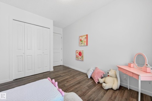 Interior room featuring wood-finish flooring, white walls, and a bi-fold closet with panel detailing - 14522 56 Street, Edmonton, AB - Indoor Photo Showing Bedroom