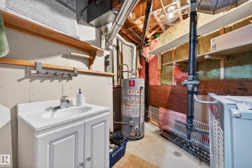 Utility room featuring a white vanity with integrated sink, wood shelving, and storage - 14522 56 Street, Edmonton, AB - Indoor Photo Showing Basement