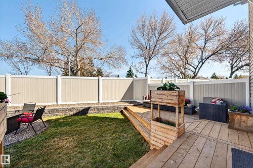 Multi-level backyard featuring a spacious wood-decked patio, a manicured lawn, a gravel seating area, and a privacy fence - 14522 56 Street, Edmonton, AB - Outdoor With Deck Patio Veranda