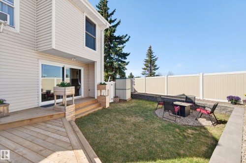 Expansive backyard featuring a wood deck, sliding glass patio door, manicured lawn, and a gravel seating area with retaining walls - 14522 56 Street, Edmonton, AB - Outdoor With Deck Patio Veranda