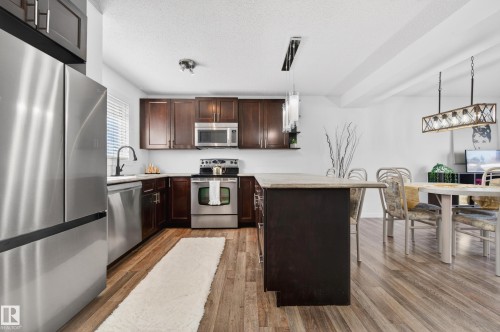 Kitchen featuring wood-finish flooring, dark wood cabinetry, and stainless steel appliances - 14522 56 Street, Edmonton, AB - Indoor Photo Showing Kitchen With Stainless Steel Kitchen