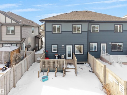 Rear exterior featuring dark blue horizontal siding and a brown shingle roof - 8921 217 Street Nw, Edmonton, AB - Outdoor With Deck Patio Veranda