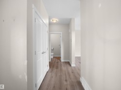 Hallway featuring wood-finish flooring, white baseboards, and a flush-mount ceiling light fixture - 