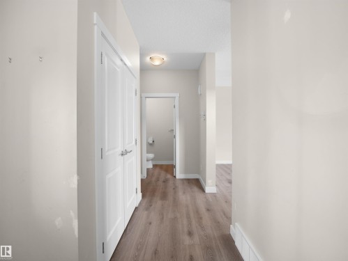 Hallway featuring wood-finish flooring, white baseboards, and a flush-mount ceiling light fixture - 8921 217 Street Nw, Edmonton, AB - Indoor Photo Showing Other Room