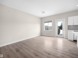 Spacious living area featuring wood-finish flooring, white baseboards, and neutral wall tones - 