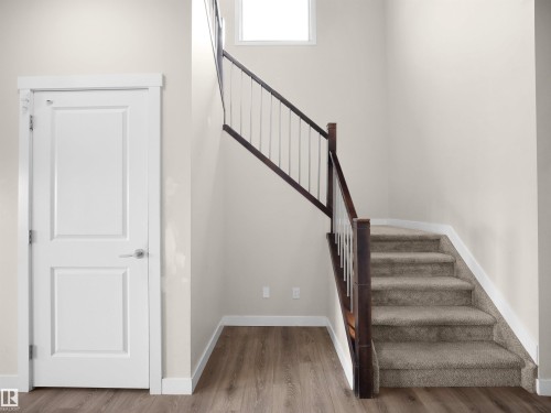 Staircase featuring dark wood newel posts and handrail with white balusters, complemented by plush carpeting - 8921 217 Street Nw, Edmonton, AB - Indoor Photo Showing Other Room