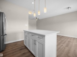 Kitchen island featuring a white countertop, white shaker-style cabinetry, and brushed nickel hardware - 