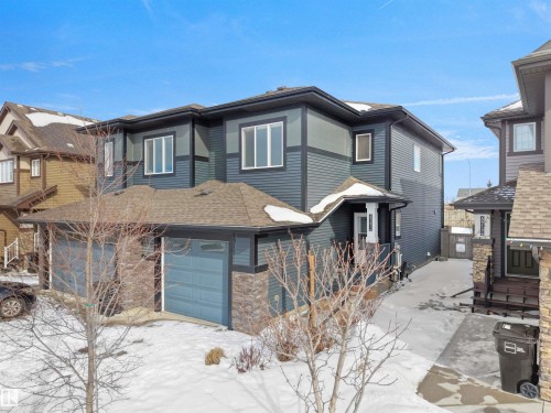 Contemporary two-story exterior featuring dark blue siding with lighter blue accents and stone veneer details - 8921 217 Street Nw, Edmonton, AB - Outdoor