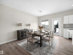 Open-concept dining area featuring light-toned wood-finish flooring, a white trim package, and a glass-paneled exterior door - 