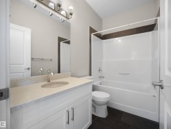 Bathroom featuring a white vanity with a light speckled countertop, an undermount sink, and a chrome faucet - 