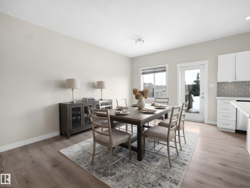 Open-concept dining area featuring light-toned wood-finish flooring, a white trim package, and a glass-paneled exterior door - 8921 217 Street Nw, Edmonton, AB - Indoor Photo Showing Dining Room