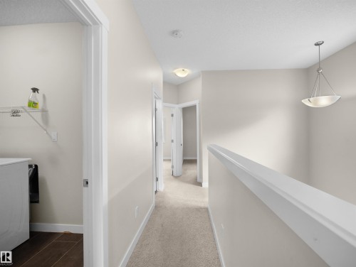 Upper-level hallway featuring neutral wall paint, carpet flooring, and a contemporary chandelier - 8921 217 Street Nw, Edmonton, AB - Indoor Photo Showing Other Room
