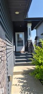 Entryway featuring a white storm door, dark exterior siding, and stone veneer accents - 