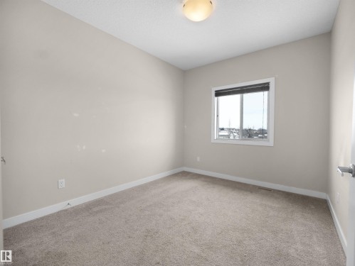 Neutral beige carpeting, light beige wall paint, white trim, and a window featuring horizontal blinds - 8921 217 Street Nw, Edmonton, AB - Indoor Photo Showing Other Room