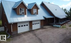 Expansive brown siding exterior featuring a multi-gable roofline with metal roofing, two dormers, and a covered porch - 