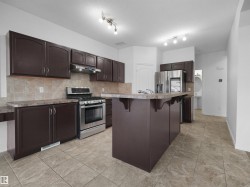 Kitchen with dark cabinetry, stainless steel appliances, and a central island with a breakfast bar - 