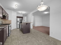 Kitchen featuring a central island, dark wood-finish cabinetry, tile flooring, and stainless steel appliances - 