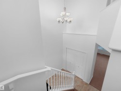 Foyer featuring a contemporary chandelier, white railings, tile flooring, and a bifold closet door - 