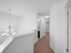 Upper hallway featuring light brown carpet flooring and white walls - 