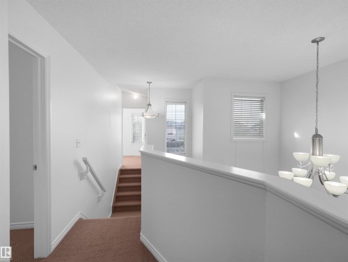 Bright upper landing featuring white walls and trim, brown carpeted flooring, and multiple windows with blinds - 2017 32A Street, Edmonton, AB - Indoor Photo Showing Other Room
