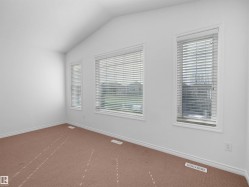 Room featuring vaulted ceilings and three distinct windows, each fitted with horizontal blinds - 