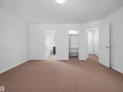 Spacious room featuring neutral carpeting, white walls, and bright overhead lighting - 